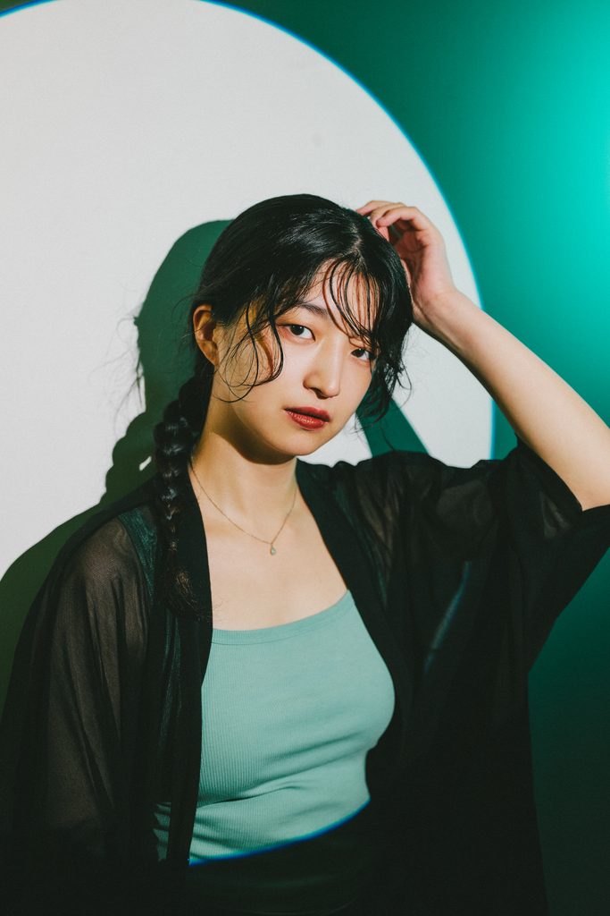 白い円形光と青緑の背景光で撮影した女性のポートレート